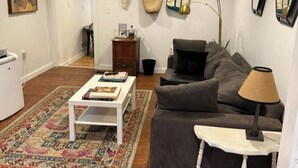 A living room with a sofa, a coffee table, a rug, a lamp, and a small cabinet. - Kingston 3 Bedroom 1 Bath Near the Rondout (Kingston)