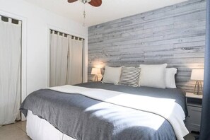 A bedroom with a bed, curtains, a wooden headboard, and bedside lamps. - Peacock 2 in Fort Lauderdale (Fort Lauderdale)