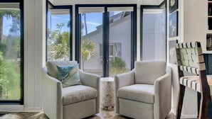 A room with two armchairs facing a sliding glass door leading to a garden. - Award-Winning Resort Amenities | Racquet Club Villa 37 (Isle of Palms)