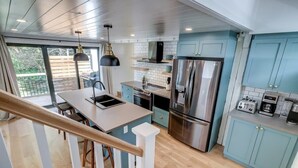 A modern kitchen with a central island, stainless steel appliances, and light blue cabinetry. - 3-bedroom house 915A Shefford mountain view (Bromont)