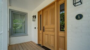 A wooden door with a black handle, a white brick wall, and a window with a white frame. - 3-bedroom house 915A Shefford mountain view (Bromont)