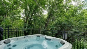 A hot tub surrounded by a metal fence with a forested background. - condo 3 chambres avec foyer,837 shefford suite 200 (Bromont)