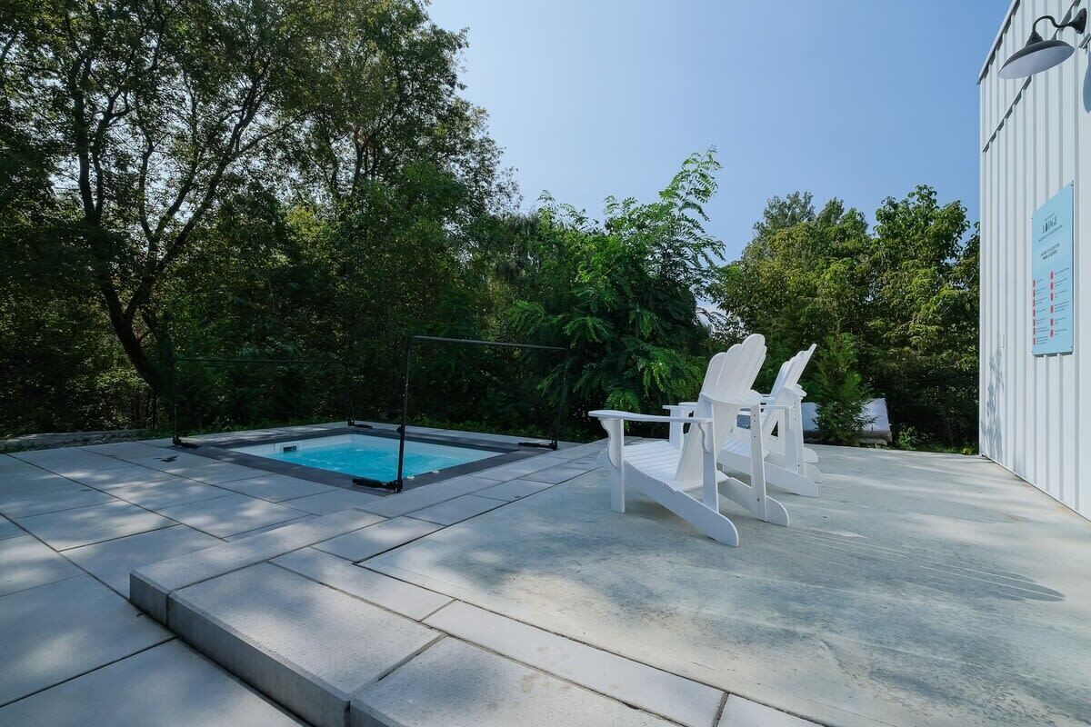 A swimming pool with a deck, two white lounge chairs, and a building with a signboard.