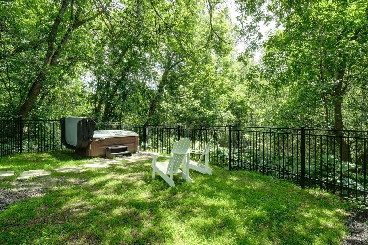 Un jardin avec une terrasse en bois, un barbecue et une chaise Adirondack blanche.