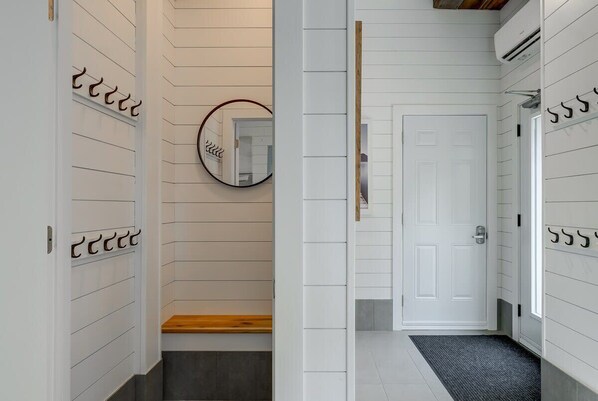 A hallway with a white door, a mirror, and a wooden bench.