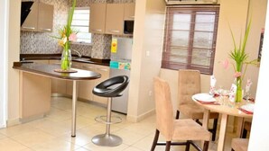 Una cocina moderna con una isla central, taburetes de bar y un comedor con una mesa dispuesta para dos personas.