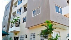 Un edificio de varios pisos con balcones, techo plano y un patio empedrado.