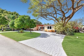 A house with a paved driveway leading to a front door, surrounded by well-maintained lawns and trees. - 401 Wilton Manors in Wilton Manors (Wilton Manors)