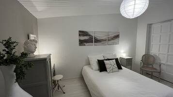 Een slaapkamer met een bed, een bureau, een stoel, een borstbeeld en abstracte decoratie aan de muur.