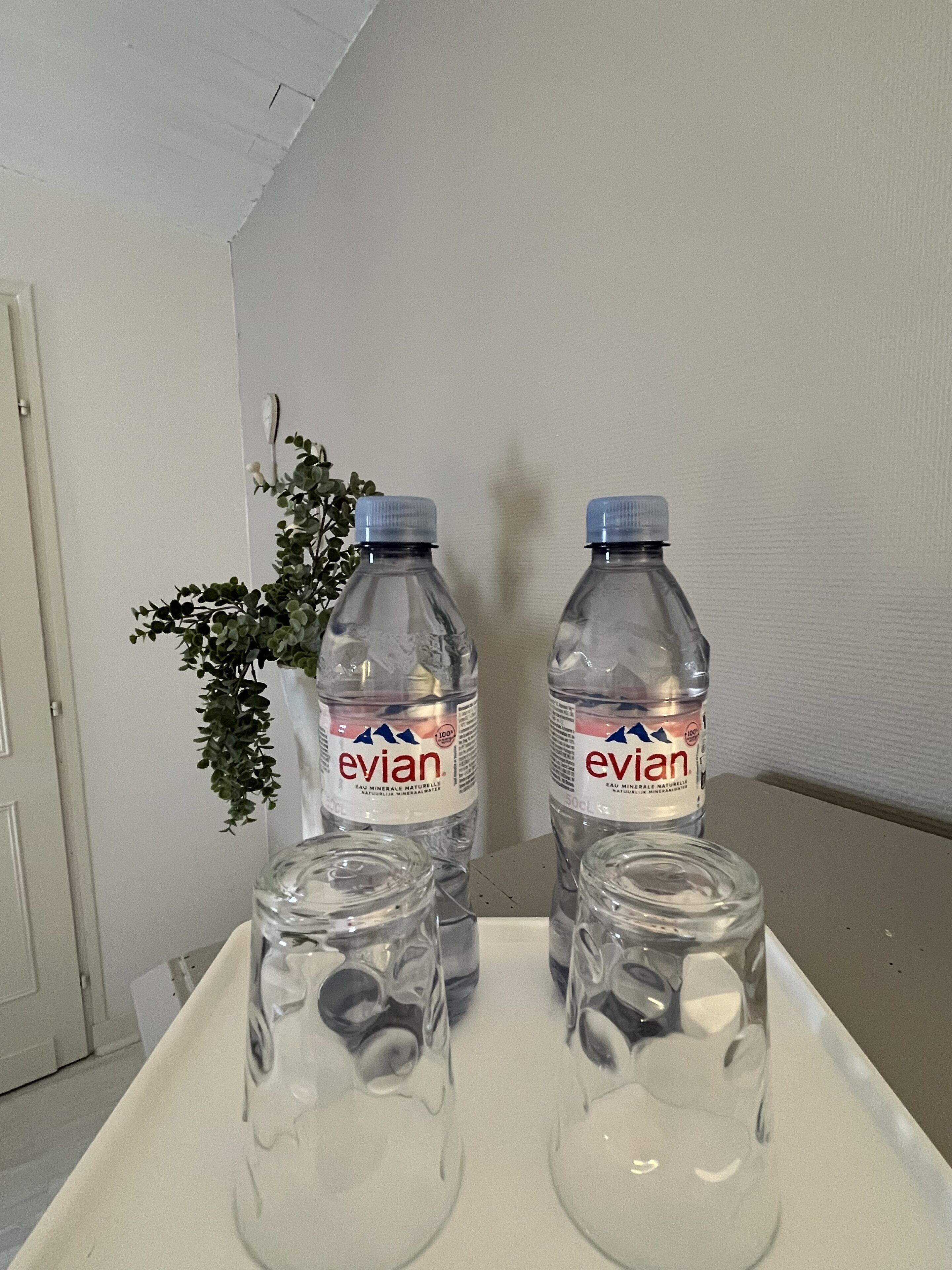 Deux bouteilles d’eau Evian et trois verres vides sur un plateau.