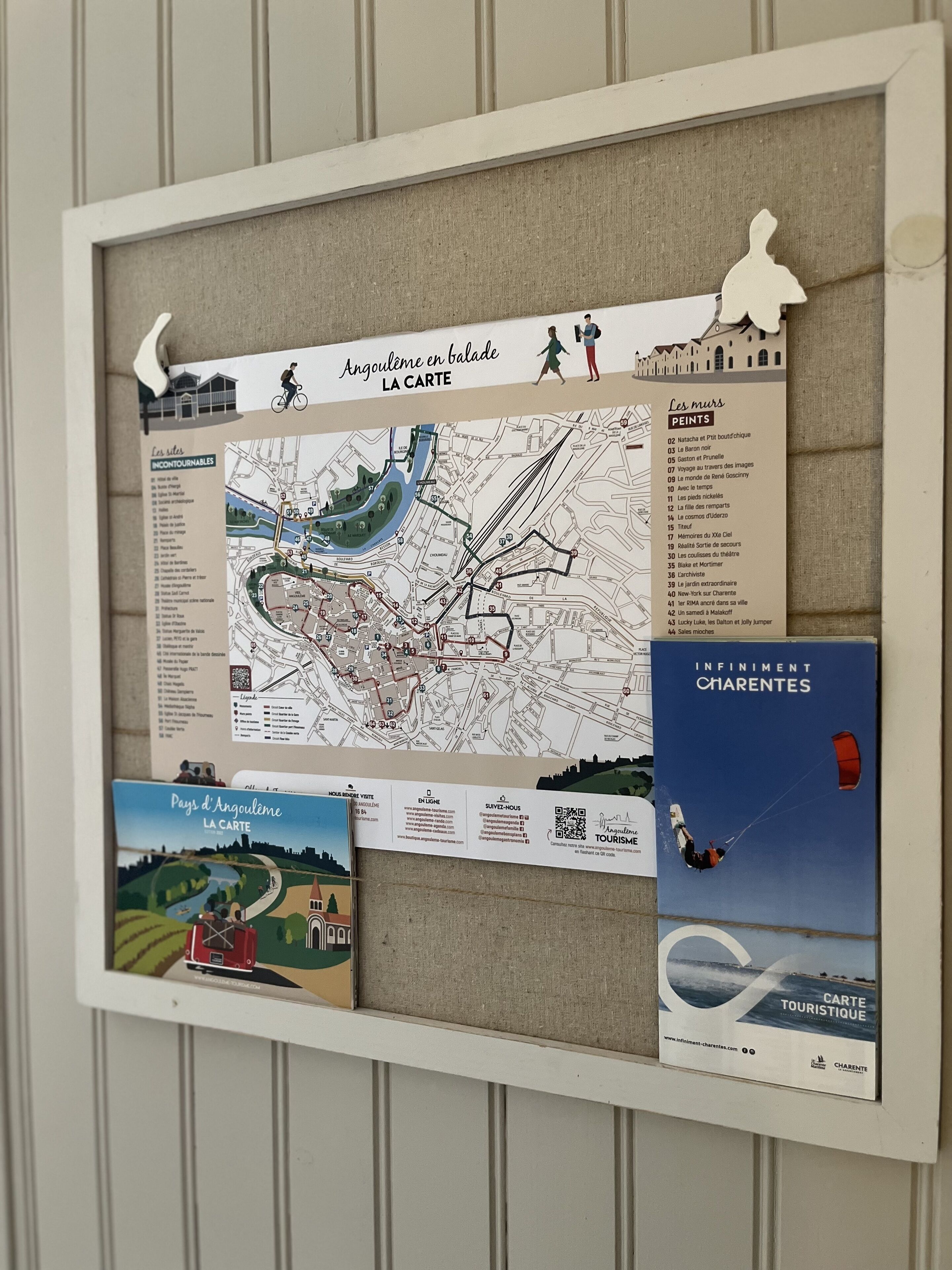 Un panneau d’affichage avec une carte, une liste des principaux lieux d’intérêt et des brochures sur Angoulême, proposées par les offices de tourisme « Angoulême en Balade » et « Infinit Charentes ».