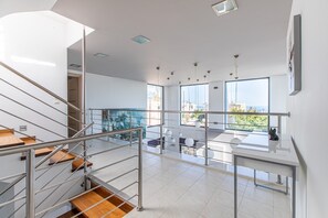 Un intérieur moderne avec un escalier, une balustrade en verre et une vue sur la ville.