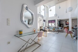 Un vaste espace de vie agrémenté d’une table basse moderne en verre, d’un canapé et d’un miroir mural original.