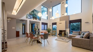 Amplia sala de estar con mesa de vidrio, sillas modernas, sofá y chimenea.