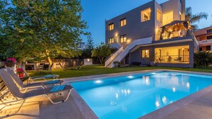 Una casa moderna de dos pisos con piscina, mobiliario exterior y una escalera que conduce a un balcón.