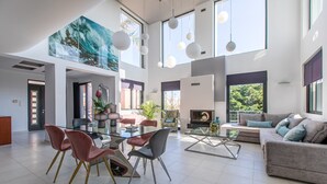 Amplia sala de estar con una mesa de comedor de vidrio, sofás modernos y un cuadro grande.