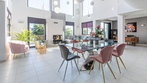 Un salón amplio con una mesa de comedor de vidrio, sillas modernas y un gran ventanal con vistas al exterior.