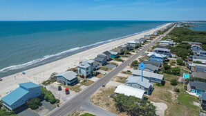 A coastal residential area with houses along the beach, a clear road, and a blue marker.