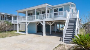 A two-story beachfront house with a covered patio, a staircase, and a number '3904' on the side.