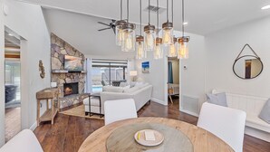 A modern living room with a stone fireplace, a round dining table, and a cozy seating area.
