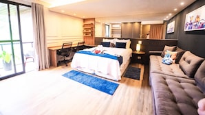 Habitació d'hotel moderna amb un llit gran, un sofà, un escriptori i una finestra ampla.