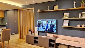 Un saló modern amb televisió de pantalla plana, separador de llibres de fusta i prestatges decoratius.