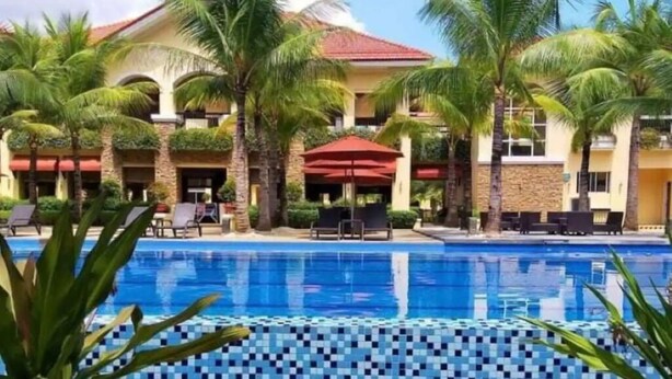 Un hotel amb piscina envoltada de palmeres i gandules.