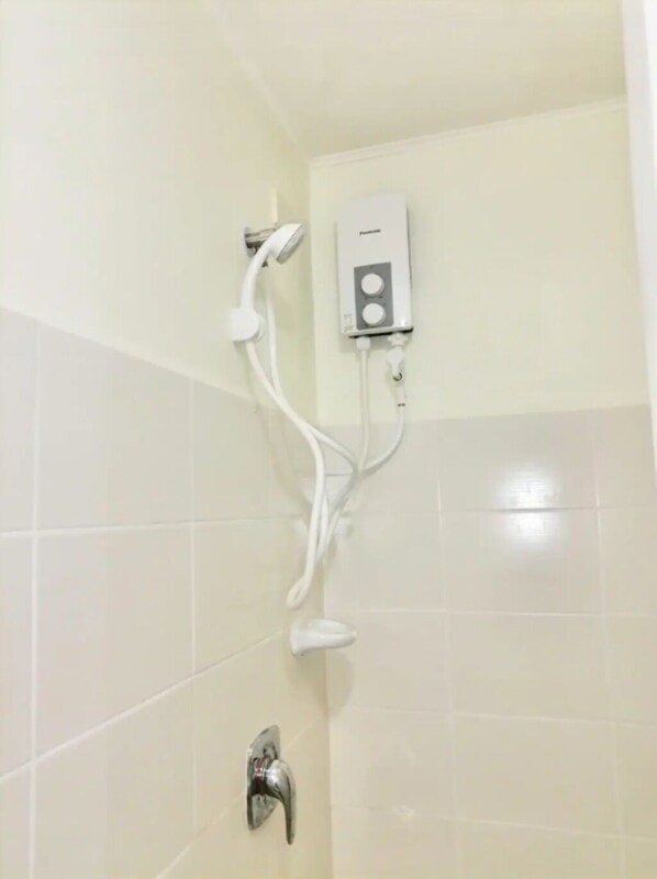 A shower with a handheld showerhead and a wall-mounted control panel.