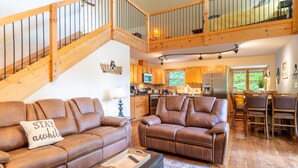 Ein großzügiges Wohnzimmer mit zwei braunen Ledersofas, einem Couchtisch und einer Treppe, die in einen oberen Bereich führt.
