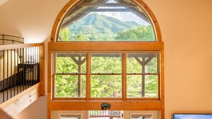 Ein Zimmer mit einem großen Bogenfenster mit Blick auf eine gebirgige Landschaft.