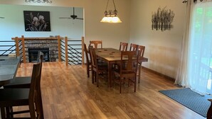 Un comedor con una mesa y sillas de madera, una chimenea y un ventilador de techo.