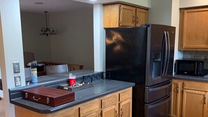 Una cocina con armarios de madera, un refrigerador negro y un microondas.
