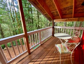 Enjoy a serene forest view from this deck with a table and chair.