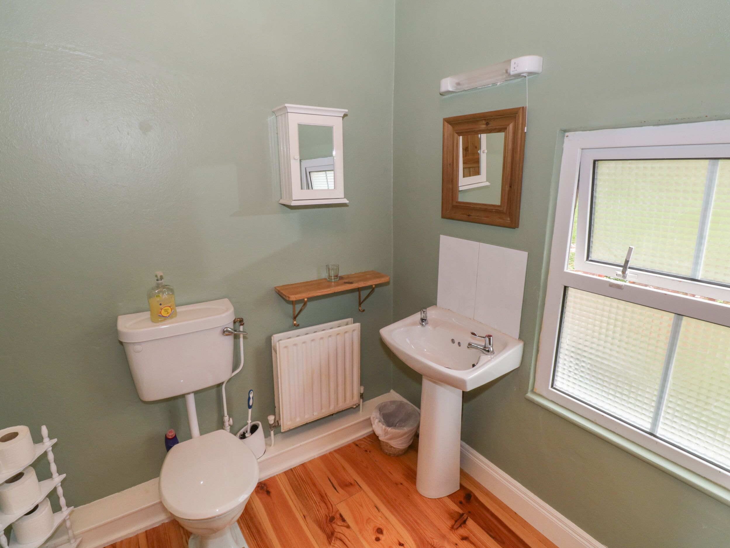 A bathroom with a toilet, sink, and window.