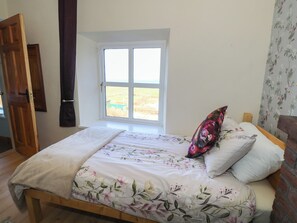 A bedroom with a bed, a window, a door, and a floral wallpaper. - Sea View House (Renvyle)