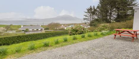 A gravel path leading to a picnic table with a scenic view of houses, greenery, and a distant mountain.