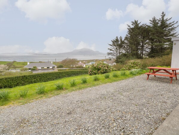 A gravel path leading to a picnic table with a scenic view of houses, greenery, and a distant mountain.