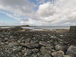 A rocky shoreline with a view of the sea and distant land.
