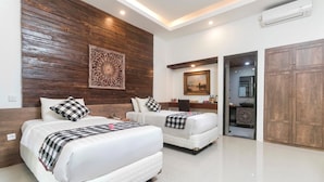 A hotel room with two beds, a wooden accent wall, a decorative panel, a framed picture, a wardrobe, and an air conditioning unit. - Nawasakti Resort (Ubud)