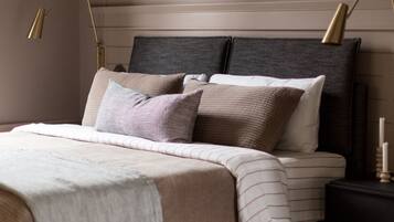 Un dormitorio ordenado con cama, mesitas de noche y lámparas.