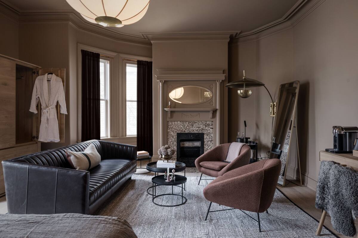 Un salon avec un canapé en cuir noir, un fauteuil marron, une table basse ronde et une cheminée.