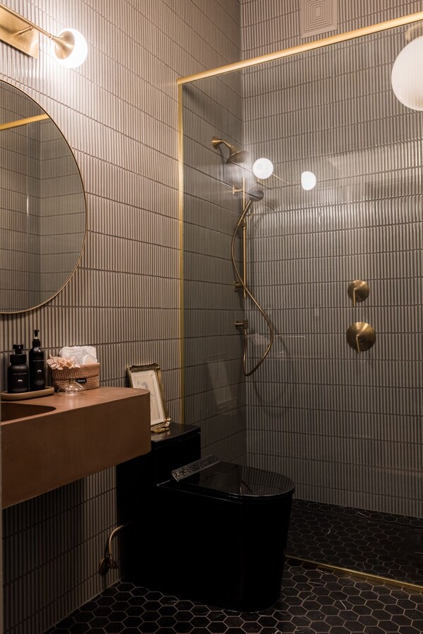 Une salle de bain moderne avec un miroir rond, un lavabo et un espace douche.