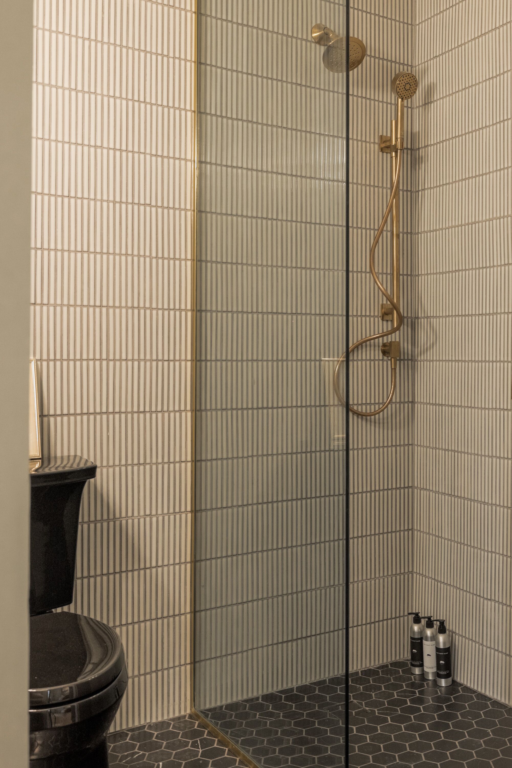 Un baño con ducha, inodoro y paredes revestidas de azulejos.