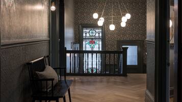 Um corredor com um banco de madeira, um candelabro e uma janela de vitrais.