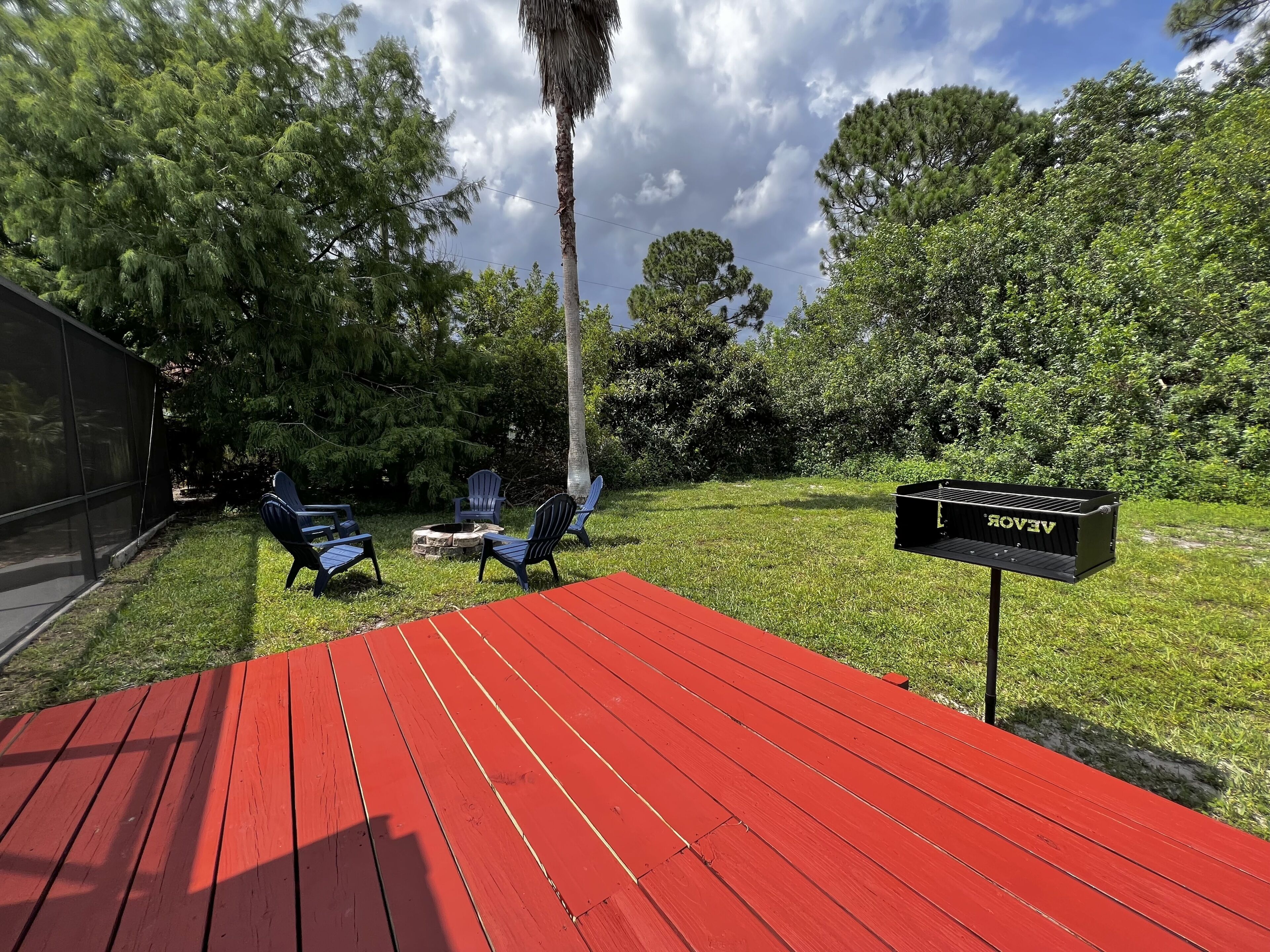 A red deck with outdoor seating, a mailbox, and lush greenery.