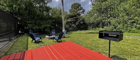 A red deck with outdoor seating, a mailbox, and lush greenery.