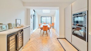 Una cocina moderna con comedor, suelo de madera y electrodomésticos integrados.