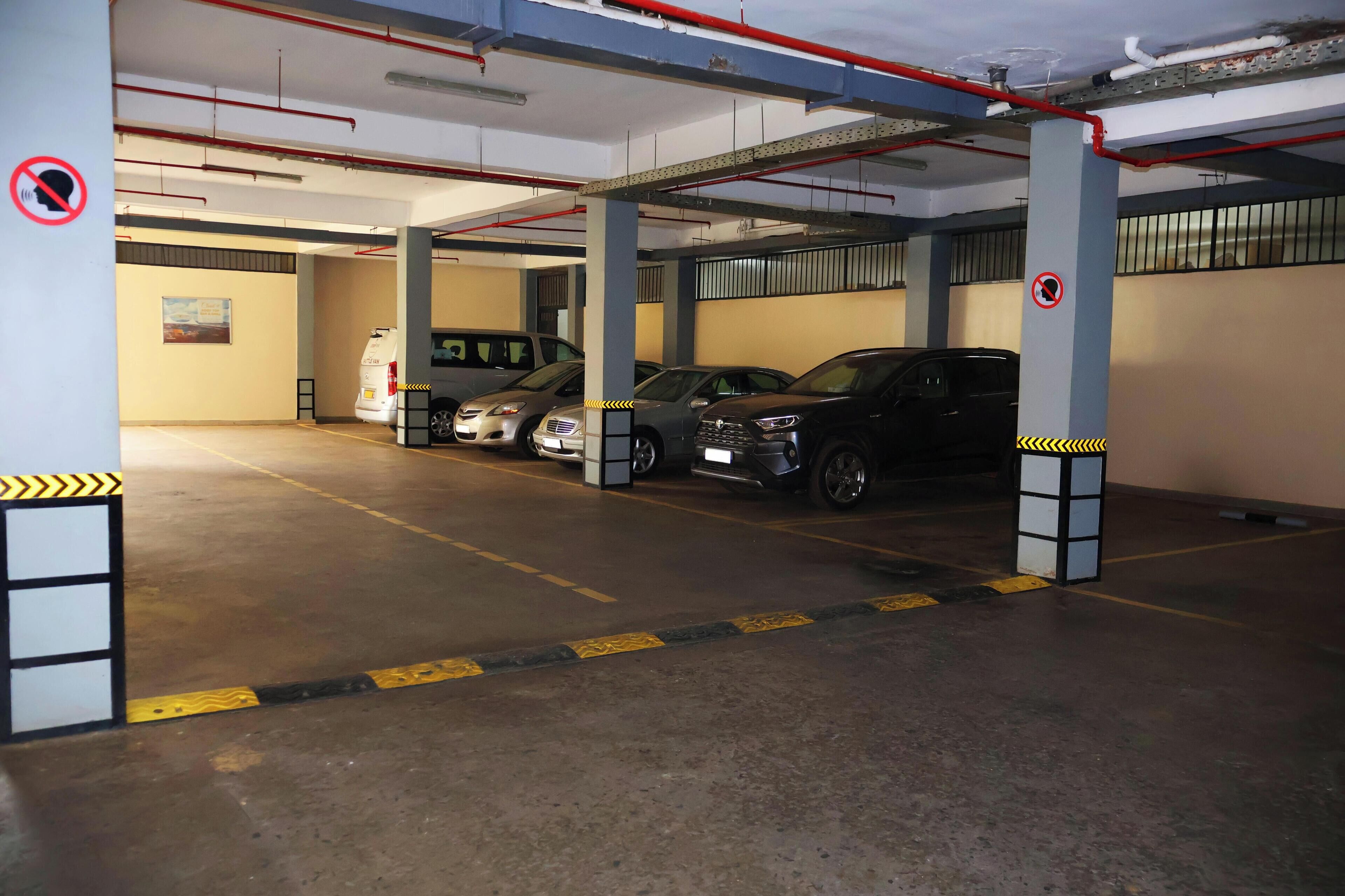 A multi-level parking garage with several cars parked, concrete floors, and structural columns.