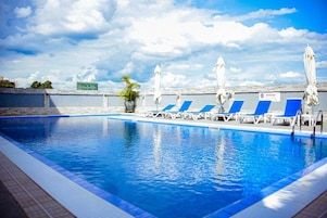 A swimming pool with blue water, white lounge chairs, and umbrellas.