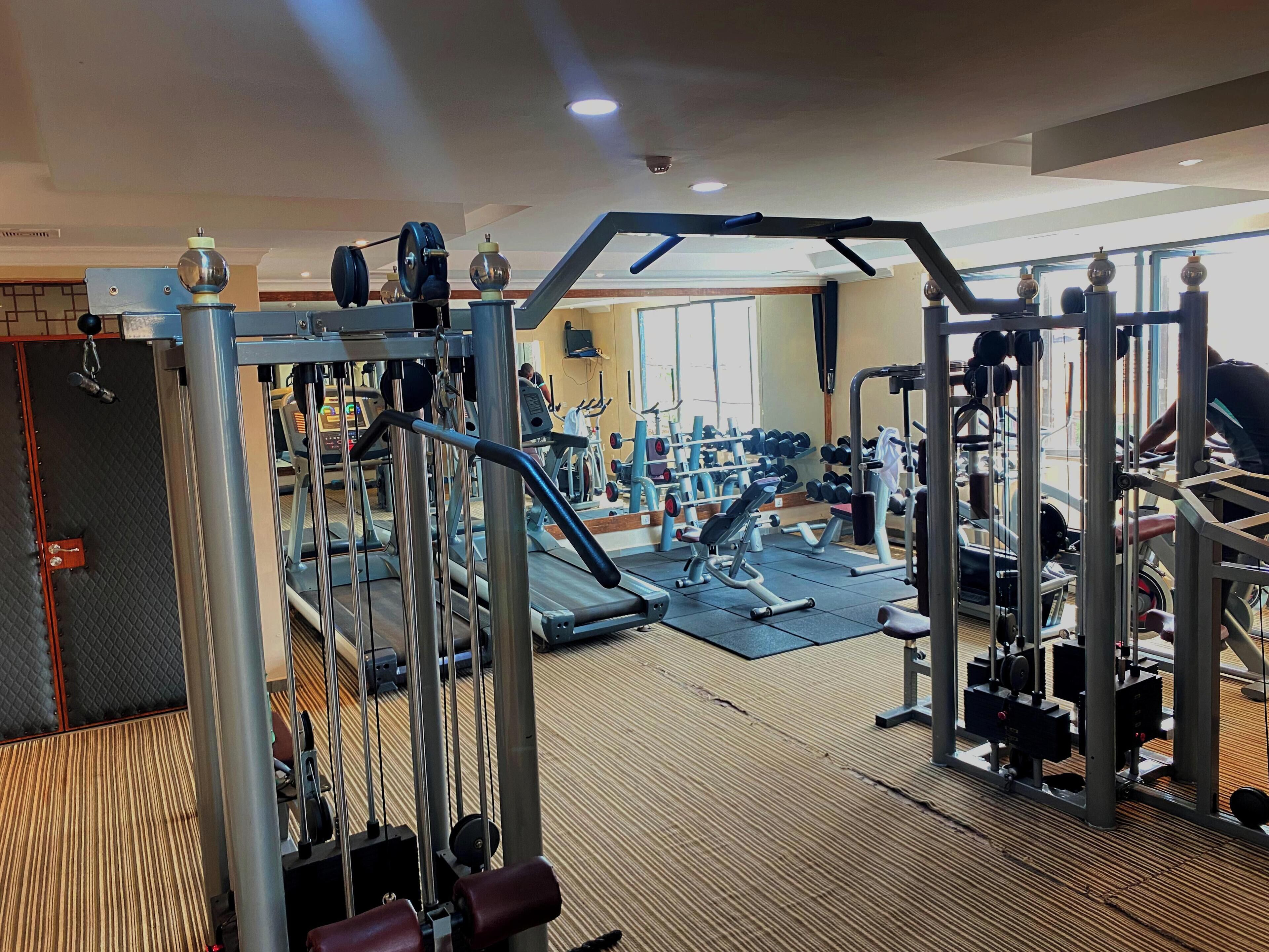 Una palestra con diverse macchine per esercizi, tapis roulant e pesi.